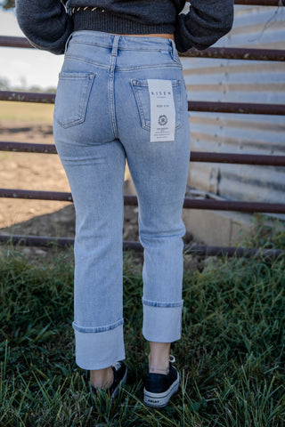 Person wearing light blue jeans with a visible brand label, standing outdoors.