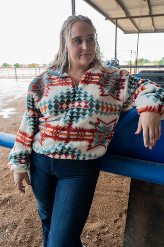 Person wearing a patterned sweater leaning against a blue structure outdoors.