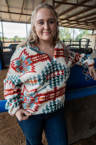 Person wearing a patterned sweater standing inside a building with a blue object in the background