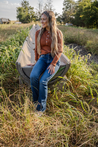 Woman sitting on a chair in a field with trees in the background