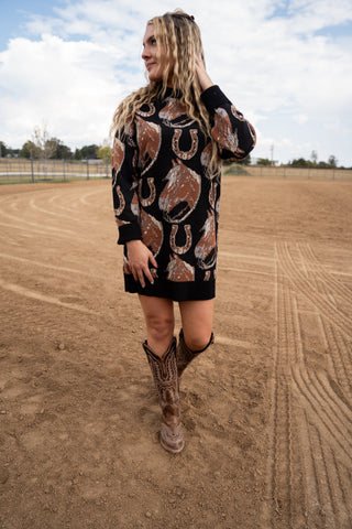 Woman wearing a patterned dress and cowboy boots on a dirt field