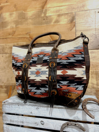 Patterned bag with leather straps on a wooden surface