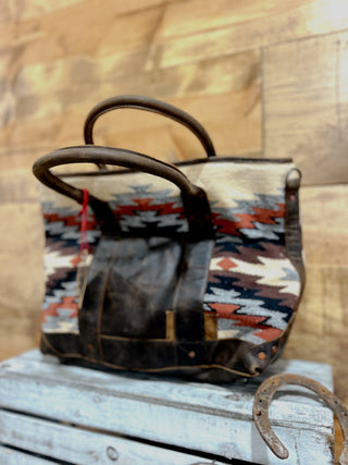 Handbag with patterned fabric and leather handles on a wooden surface