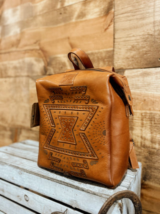 Brown leather backpack with embossed design on a wooden surface