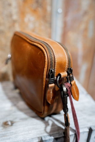 Brown leather bag with a strap on a textured surface