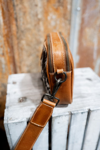 Brown leather bag with a strap on a wooden surface