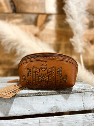 Brown leather pouch with intricate designs on a wooden surface with a soft, blurred background.