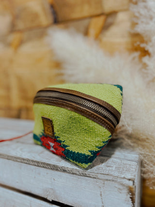 Green embroidered pouch with a zipper on a wooden surface