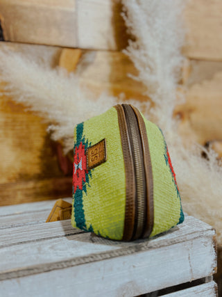 Small green fabric pouch with a zipper on a wooden surface