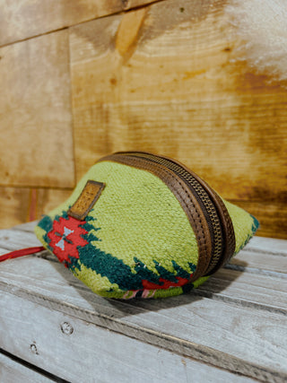 Green knitted pouch with a brown zipper on a wooden surface