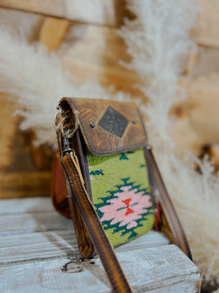 Small leather pouch with a colorful patterned strap on a wooden surface