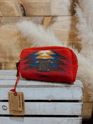 Red patterned pouch with a brand tag on a wooden surface