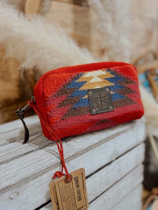 Red patterned pouch with 'sts' label on a wooden surface
