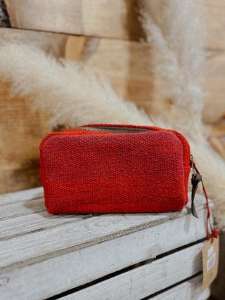Red textured pouch on a wooden surface with a blurred background