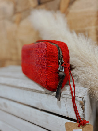 Red textured pouch with a strap on a wooden surface