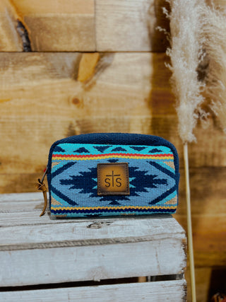 Blue patterned pouch with a logo on a wooden surface
