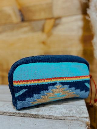 Blue woven pouch with colorful stripes on a wooden surface