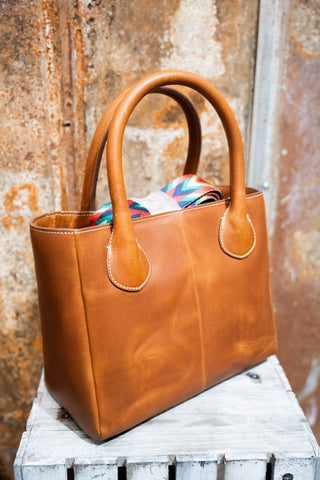 Brown leather handbag on a wooden surface with a rustic background