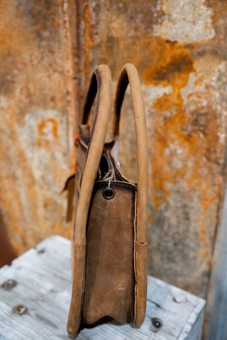 Brown leather bag on a textured surface with a rusty metal background