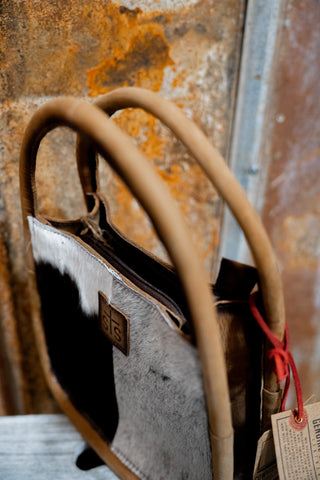 Vintage-style handbag with a textured handle against a rusty metal background