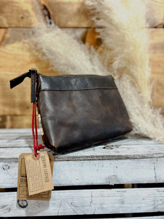 Brown leather pouch with tags on a wooden surface