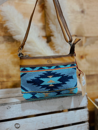 Blue patterned handbag with brown strap on a wooden surface