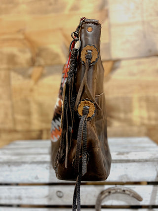 Brown leather handbag with decorative elements on a wooden surface