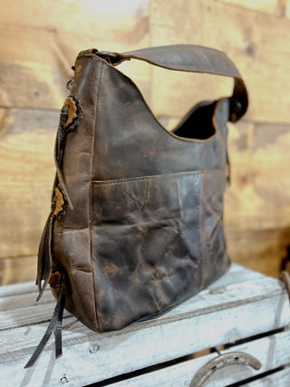 Brown leather bag with fringes on a wooden surface