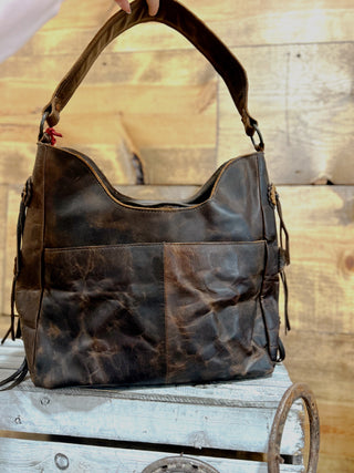 Brown leather handbag on a wooden surface with a rustic background