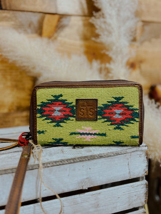 Green patterned wallet with brown leather strap on a wooden surface