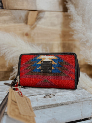 Red and black patterned wallet with a tag on a wooden surface