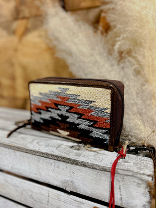 Woven patterned wallet with a red string on a wooden surface