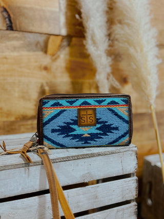Blue patterned wallet with a brown strap on a wooden surface