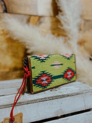 Handmade green pouch with red floral patterns on a wooden surface