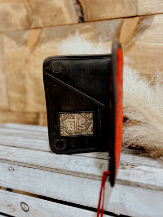 Black leather wallet with geometric design on a wooden surface