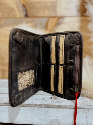 Open leather wallet with decorative elements on a wooden surface
