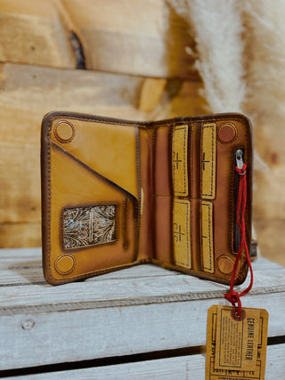 Brown leather wallet with decorative elements on a wooden surface