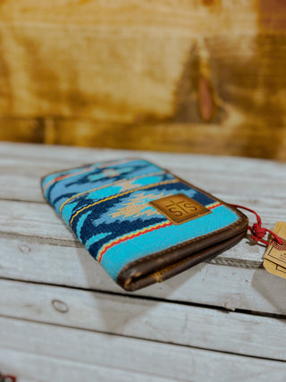 Blue patterned pouch with brown leather accents on a wooden surface