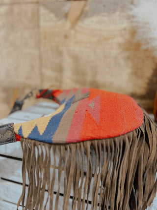 Textile with colorful pattern and fringes on a wooden surface