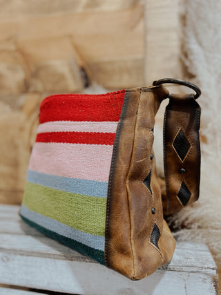 Colorful striped pouch with a leather strap on a wooden surface