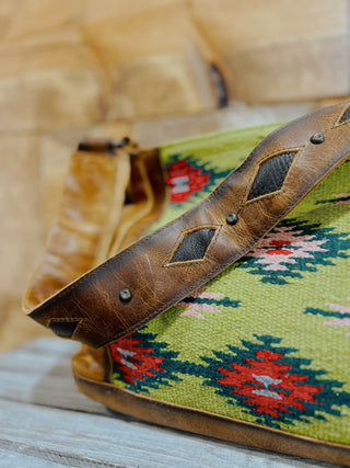 Close-up of a brown leather strap with decorative patterns on a green fabric background.