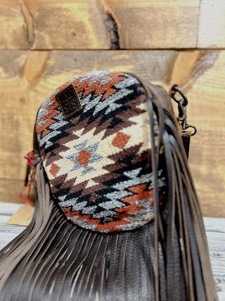 Handbag with tribal pattern and fringes on a wooden surface