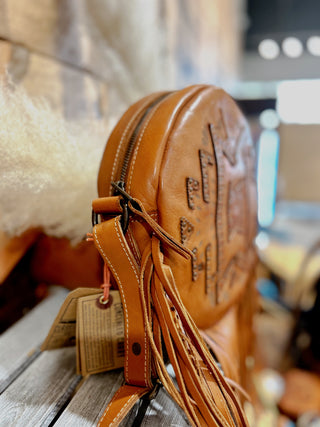 Brown leather bag with tassels on a wooden surface