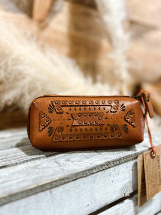 Brown leather wallet with intricate designs on a wooden surface