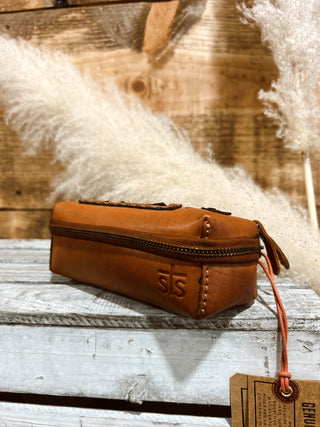 Brown leather pouch with a visible brand logo on a wooden surface.