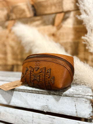 Brown leather pouch with embossed design on a wooden surface