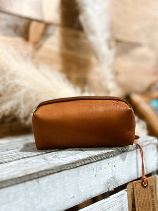 Brown leather pouch on a wooden surface with a blurred natural background