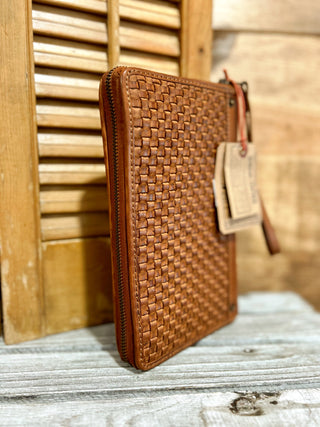 Brown woven leather pouch with a tag on a wooden surface