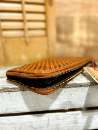Brown woven leather wallet on a wooden surface with a blurred background