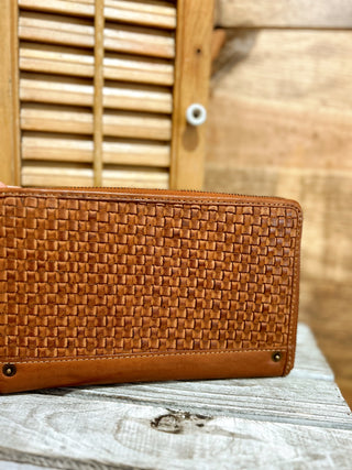 Brown woven wallet on a wooden surface with a blurred wooden background